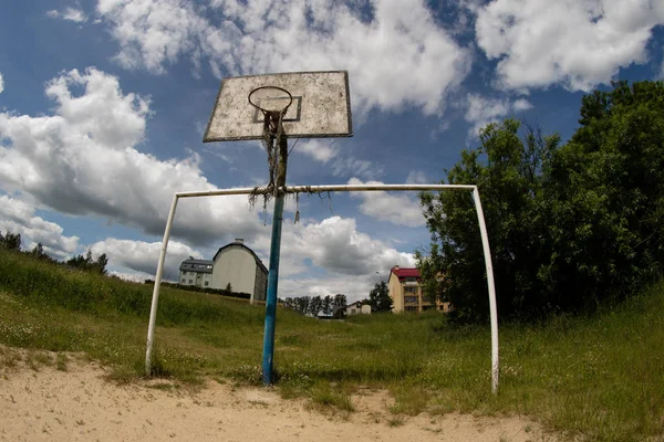 Старая баскетбольная площадка, корзина, вырванная сетка в небе — стоковое фото