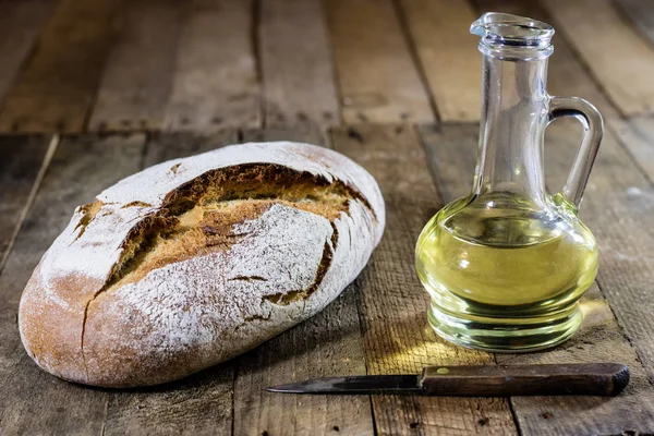 Smaczny chleb i oliwa z oliwek w szklanej butelce. Drewniane tabl — Zdjęcie stockowe