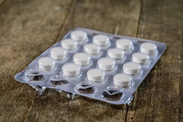 Ahşap bir masa üzerinde tıbbi tabletleri. Plastik contai beyaz hap
