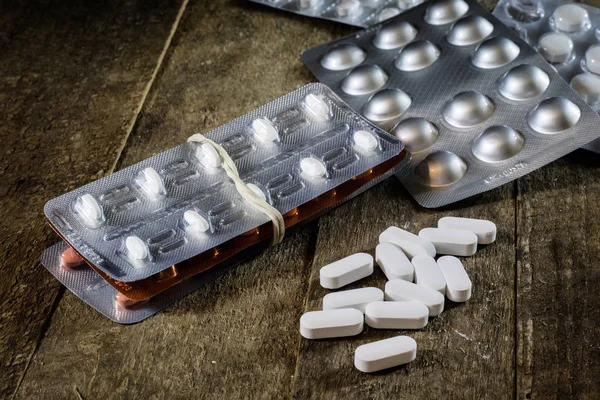 Ahşap bir masa üzerinde tıbbi tabletleri. Plastik contai beyaz hap — Stok fotoğraf