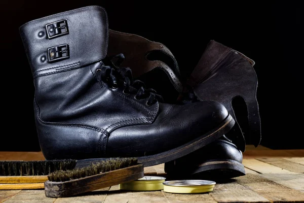 Old black Polish military boots on a wooden table. Stock Image