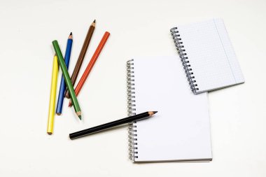 Şehvetli sketchbook ve boya kalemi beyaz bir tablo. Beyaz masa ve