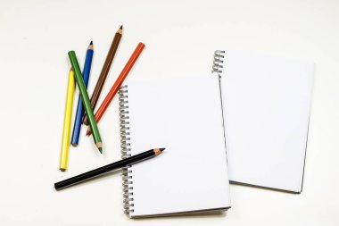 Şehvetli sketchbook ve boya kalemi beyaz bir tablo. Beyaz masa ve