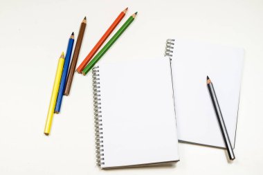 Şehvetli sketchbook ve boya kalemi beyaz bir tablo. Beyaz masa ve