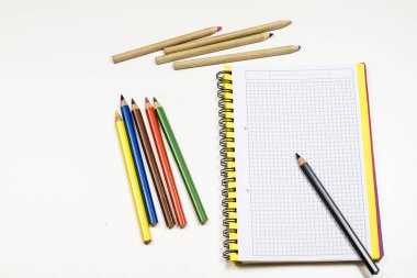 Şehvetli sketchbook ve boya kalemi beyaz bir tablo. Beyaz masa ve