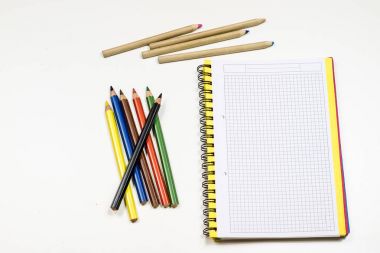 Şehvetli sketchbook ve boya kalemi beyaz bir tablo. Beyaz masa ve