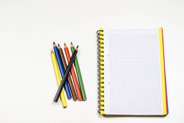 Şehvetli sketchbook ve boya kalemi beyaz bir tablo. Beyaz masa ve