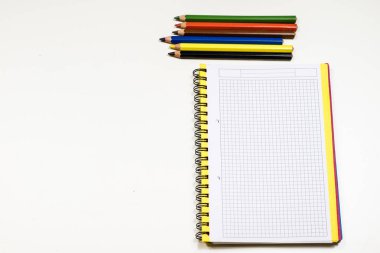 Şehvetli sketchbook ve boya kalemi beyaz bir tablo. Beyaz masa ve