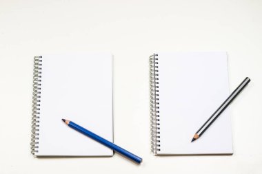 Şehvetli sketchbook ve boya kalemi beyaz bir tablo. Beyaz masa ve