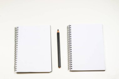 Şehvetli sketchbook ve boya kalemi beyaz bir tablo. Beyaz masa ve