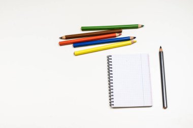 Şehvetli sketchbook ve boya kalemi beyaz bir tablo. Beyaz masa ve