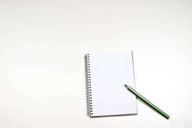 Şehvetli sketchbook ve boya kalemi beyaz bir tablo. Beyaz masa ve