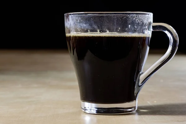 Ízletes meleg kávé habbal, egy pohár, egy fából készült asztal. — Stock Fotó
