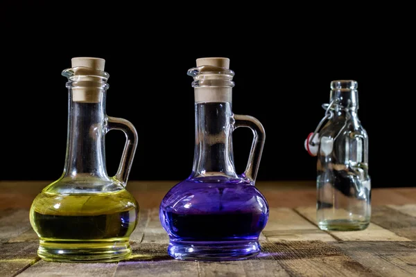 Flaschen farbiger Flüssigkeit auf einem hölzernen Küchentisch. Holztisch — Stockfoto