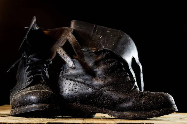 Muddy old military boots. Black color, dirty soles. Wooden table — Stock Photo, Image