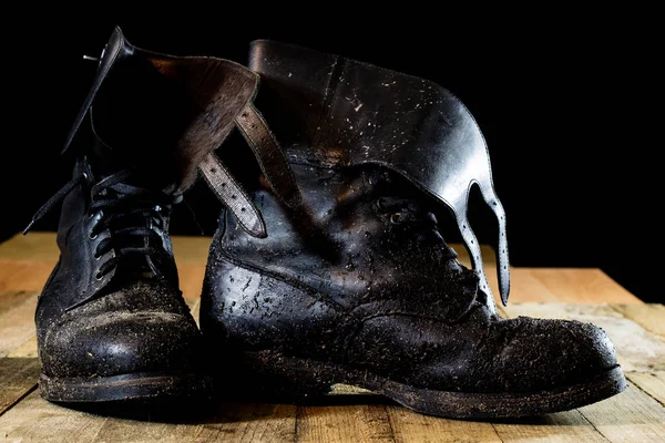 Błotniste stare buty wojskowe. Kolor czarny, brudne podeszwy. Drewniany stół — Zdjęcie stockowe