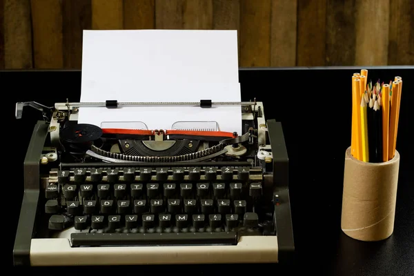 Máquina de escribir en la mesa negra. Tarjeta blanca en blanco. Pared de b áspero —  Fotos de Stock