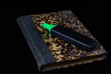 Eski kitap üzerinde siyah bir tezgah ve ofis kalemi yalan.