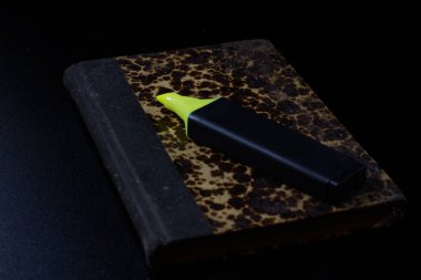 Eski kitap üzerinde siyah bir tezgah ve ofis kalemi yalan.