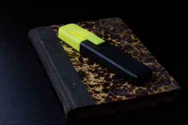 Eski kitap üzerinde siyah bir tezgah ve ofis kalemi yalan.