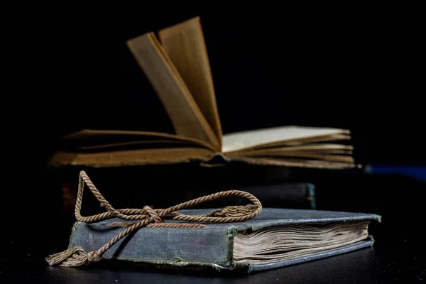 Een oud boek liggend op een zwarte tafel. Op de achtergrond een stapel — Stockfoto