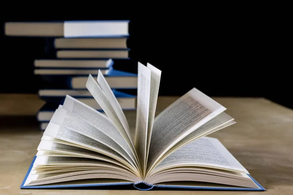 Hoopje van boeken lezen op een houten tafel. Naast ligt. Zwarte bac — Stockfoto