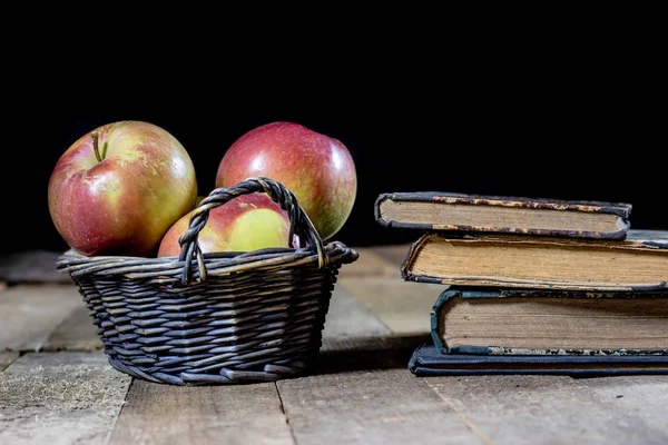 Вкусные яблоки в корзине на кухонном столе. Старые книги лежат рядом — стоковое фото