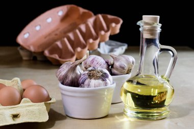 Sarımsak, yumurta ve yağı bir ahşap mutfak masasında. Mutfak pro ile