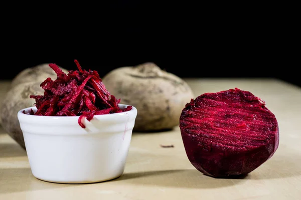 Beetroots grated on shavings. Wooden dining table. Black backgro — Stock Photo, Image