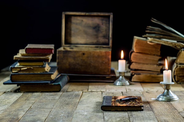 Old books and candles on a wooden table. Old room, reading room.
