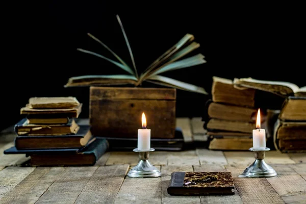 Oude boeken en kaarsen op een houten tafel. Oude kamer, leeskamer. — Stockfoto