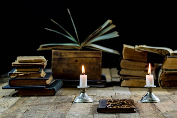 Old books and candles on a wooden table. Old room, reading room.