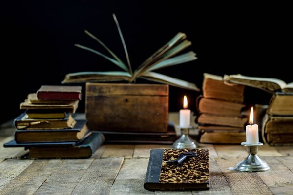 Old books and candles on a wooden table. Old room, reading room.