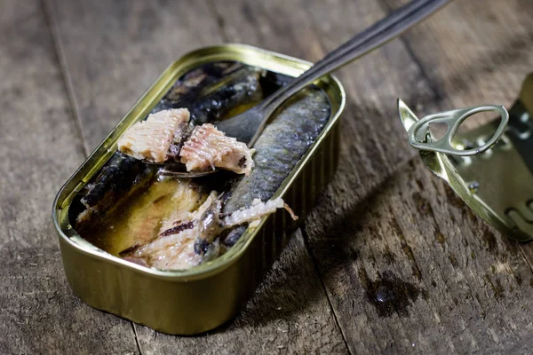 Una lattina di pesce su un tavolo da cucina in legno. Accanto alla lattina per — Foto Stock