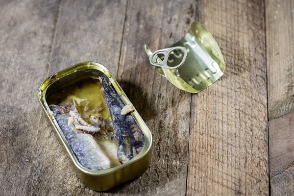 Eine Blechdose mit Fisch auf einem hölzernen Küchentisch. neben der Dose für — Stockfoto