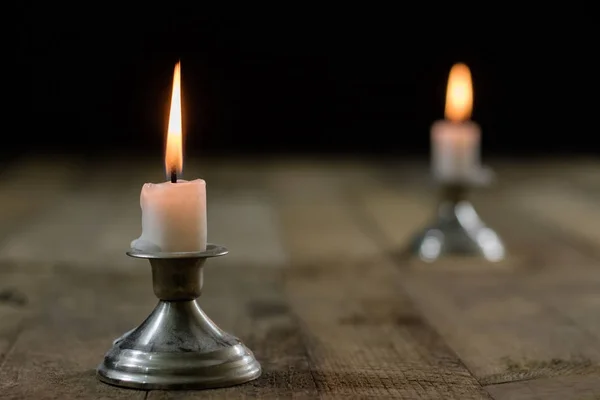 Candles burning in candlesticks on a wooden table. Silver candle — Stock Photo, Image