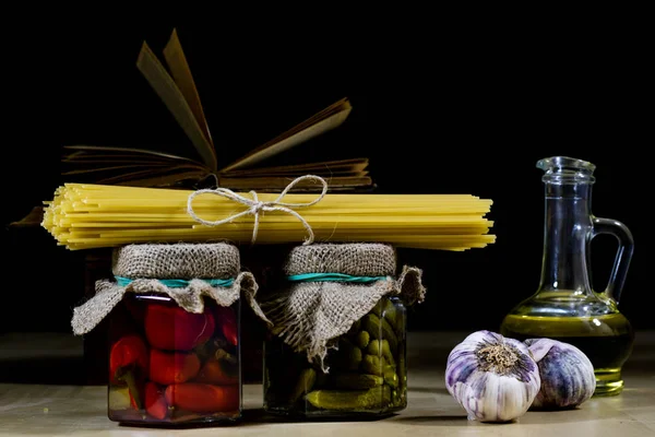 Паста и оливковое масло на старом кухонном столе. Рецепты в старой книге — стоковое фото