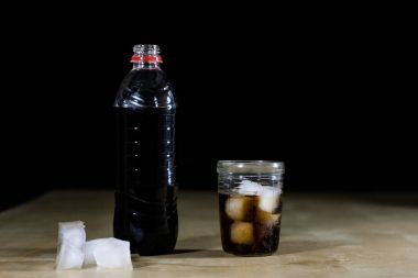 Soda ve şişe üzerinde ahşap bir masa. Bir bardak ve bir şişe bever
