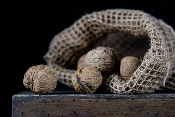 Arachidi in un sacchetto naturale. Un sacco di noci su una vecchia t di legno scuro — Foto Stock