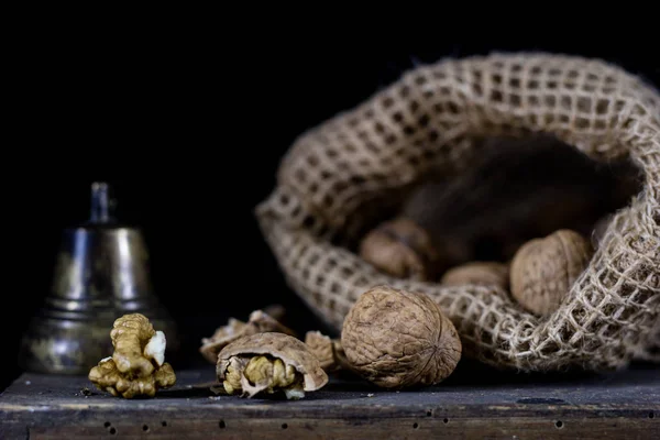 Frutta a guscio in un sacchetto naturale. Un sacchetto di noci e una campana su un vecchio buio w — Foto Stock