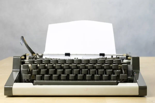 Typewriter and white card screwed into the machine. Wooden table Royalty Free Stock Photos