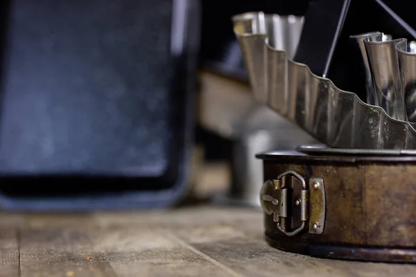 Blikken en bakken formulieren op een houten tafel. Oude keuken accessoires — Stockfoto