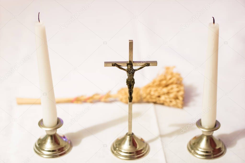 Cross and candles on a white tablecloth. Carol singing, cross an