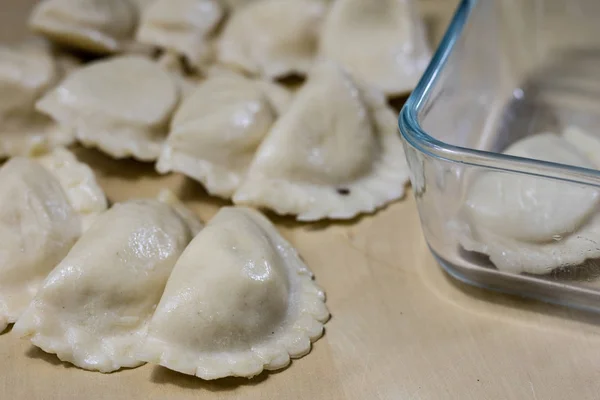Läckra dumplings ordnade på en ljus trä köksbord. Dumpli — Stockfoto