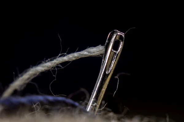 The ear of a sewing needle with a thread. The thread is threaded — Stock Photo, Image