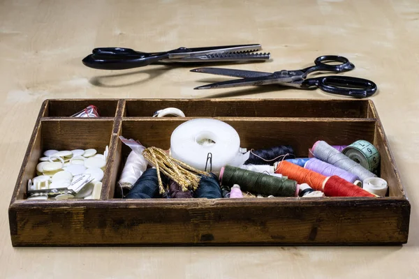 Garment accessories spread on a light wooden table. Threads, sci — Stock Photo, Image