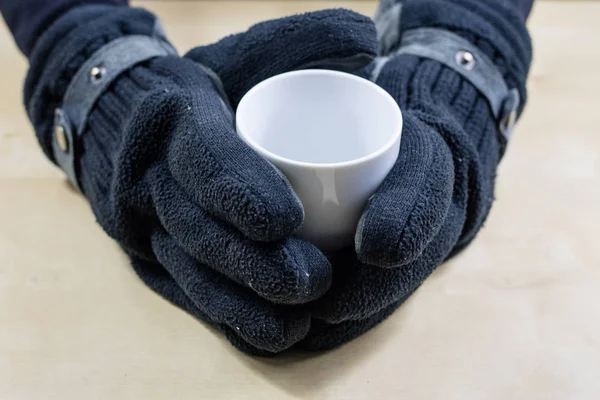 Empty white mug with gloves. Hands in warm gloves holding a chin