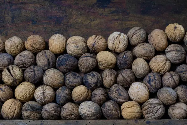 Walnuts on a wooden kitchen table. Nuts and a black wooden crate — Stock Photo, Image
