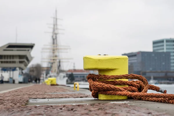 Une borne d'amarrage enlacée avec une corde d'amarrage. Navires mouillés à — Photo