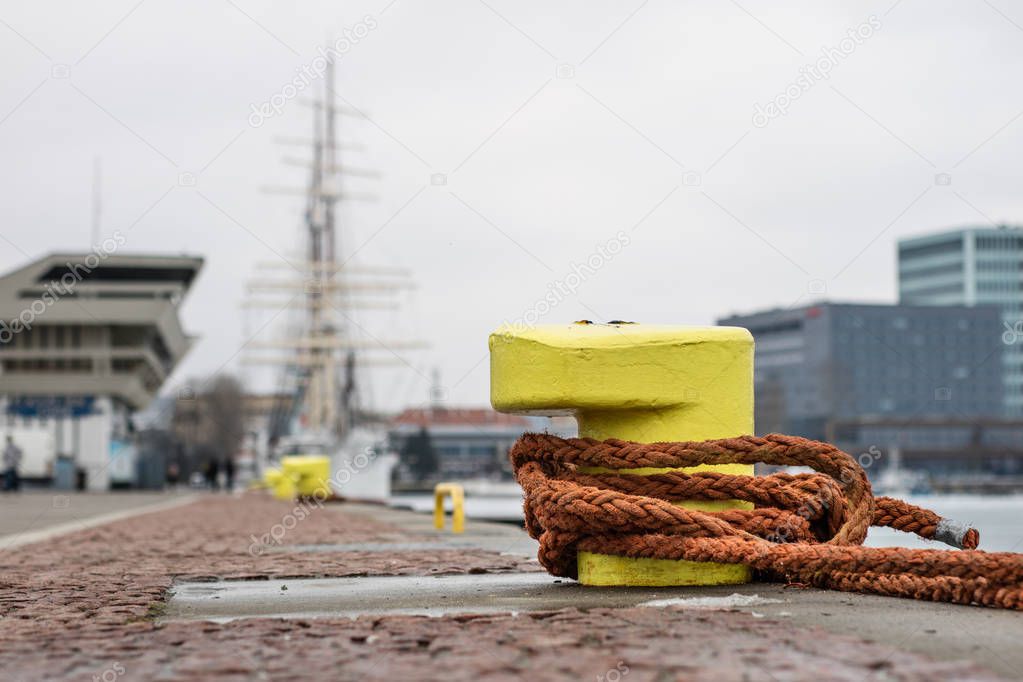 A mooring bollard entwined with a mooring rope. Moored ships at 